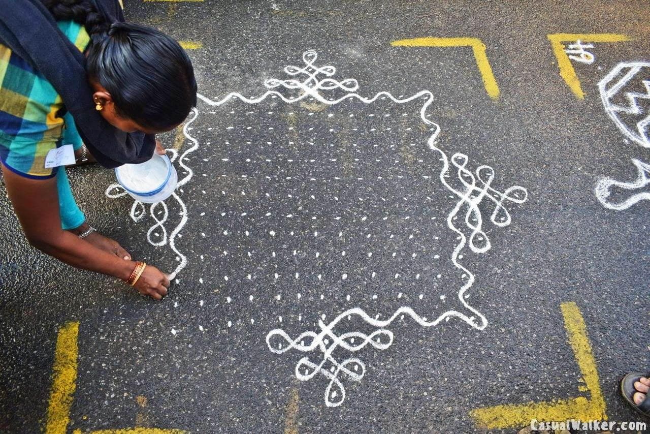 Woman drawing kolam at Mylapore Kolam Festival